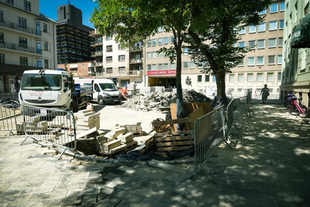 Construction site on a sunny day in Bratislava with work vehicles and building materials.